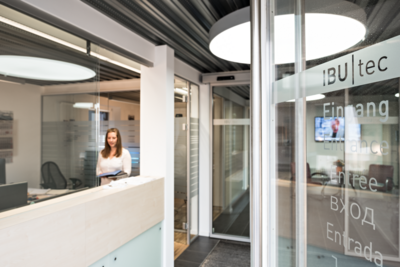 Welcome area and entry to IBU-tec's headquarters in Weimar, reception with receptionist and open glass door