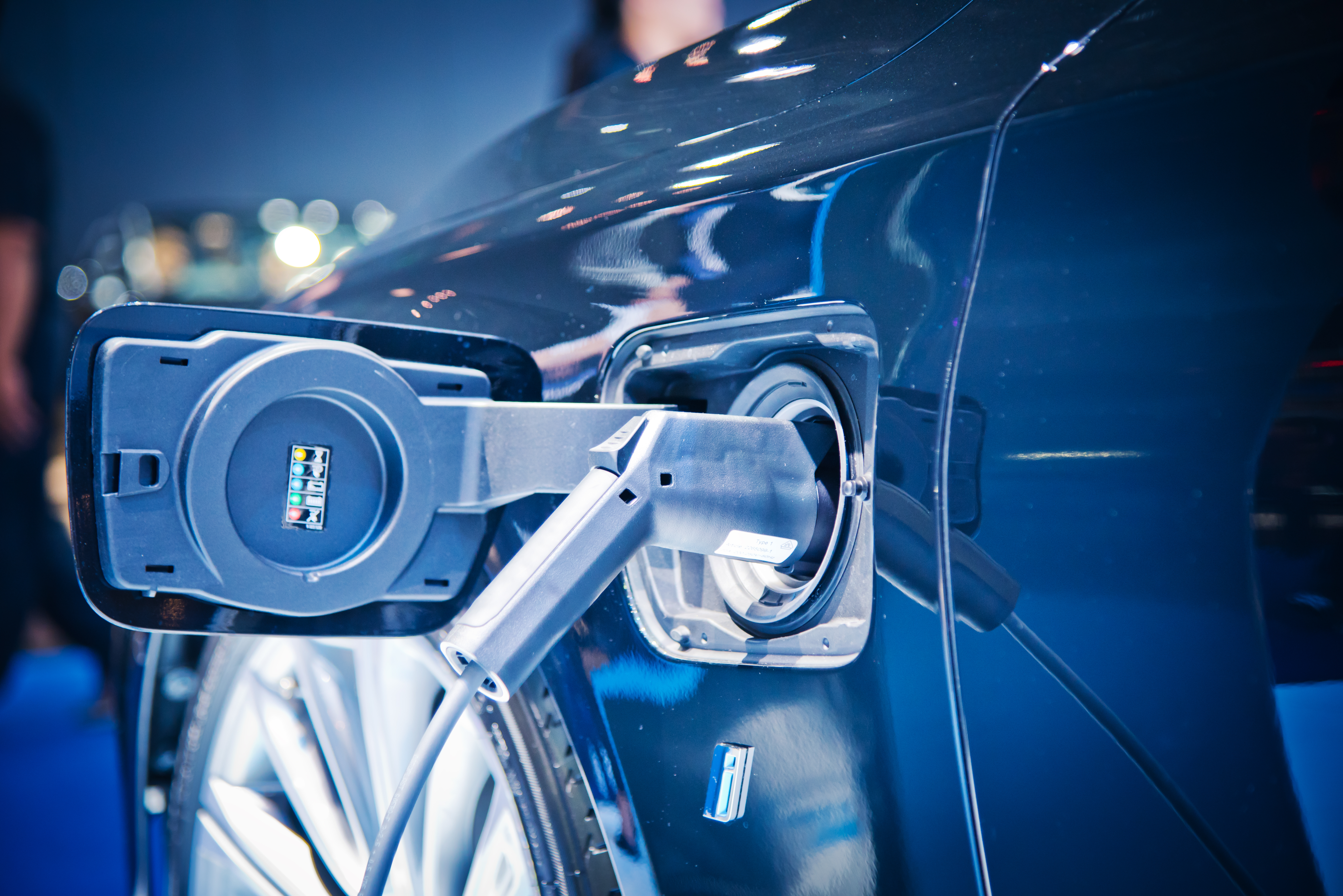 Nahaufnahme der Ladebuchse und des angeschlossenen Ladekabels an einem dunkelblauen E-Auto